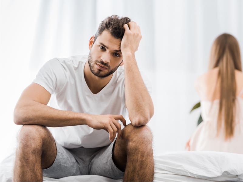 LM-does-testosterone-help-with-erectile-dysfunction-main upset man sitting on bed to illustrate wondering does testosterone help with ED
