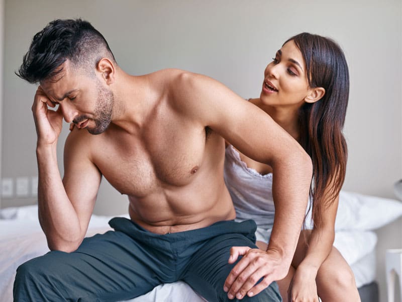 LM-foods-for-erectile-dysfunction upset man sitting on bed ignoring partner, to illustrate the need to know about foods for erectile dysfunction